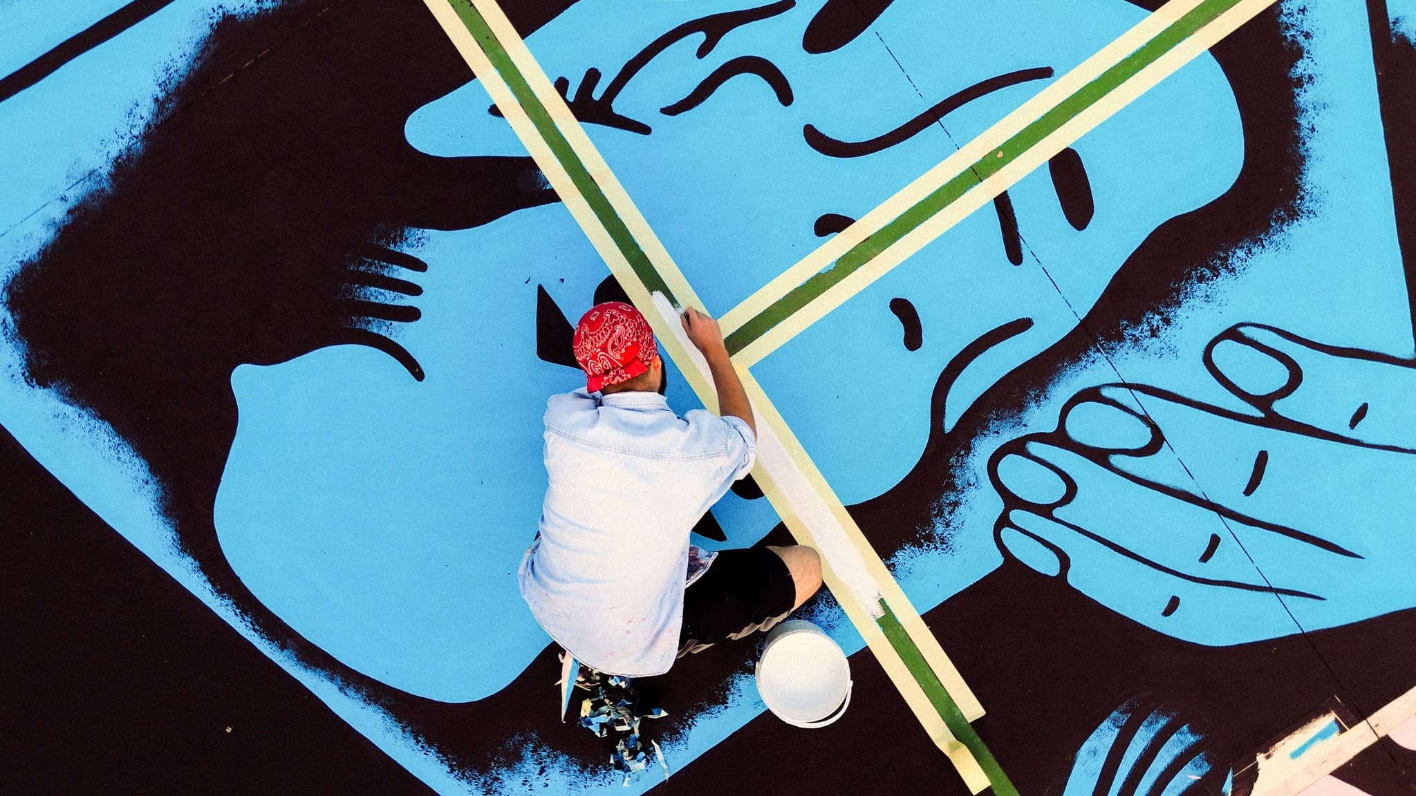 An artist painting a large mural on a basketball court